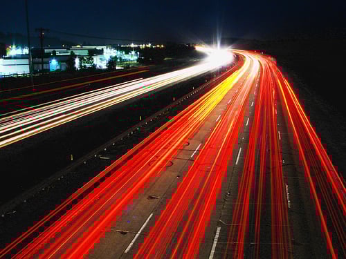 An example of light trail photography showing cars' headlights and tail lights on a busy highway. Image via digital-photography-school.com